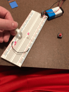 Breadboard with tactile pressure switch, voltage regulator, and two ~2V LEDs.
