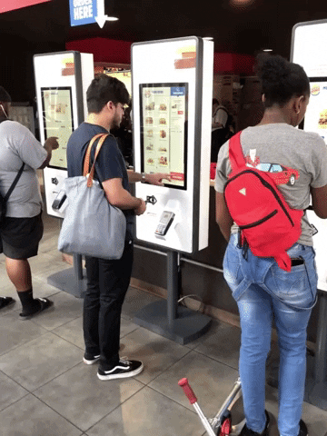 Animated GIF showing people using the ordering kiosks to place their orders at Burger King