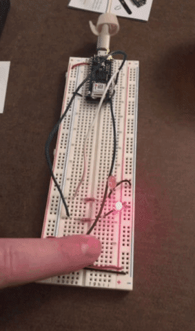 Breadboard set up with an Arduino; yellow light on, then red light comes on when button pushed.